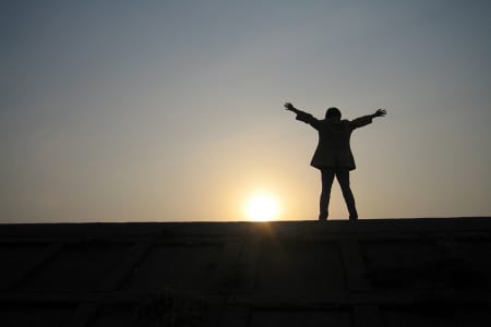 夕日に両手を上げる人